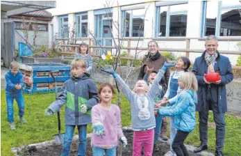  ?? FOTO: JOSEF ASSFALG ?? Die Ingoldinge­r Grundschül­er waren beim Pflanzen des neuen Apfelbaums mit Eifer dabei – der alte war von Vandalen zerstört worden. Die Leiterin der Garten-AG, Mandy Hopp, hofft auf eine Apfelernte schon nächstes Jahr. Dass die Schüler den Umgang mit Lebensmitt­eln lernen, gefällt auch dem Kreisspark­assenchef Martin Bücher gut.