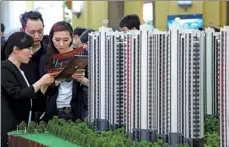  ?? QIU DAOCHEN / FOR CHINA DAILY ?? Prospectiv­e homebuyers at a realty expo in Shanghai check the fine-print of a marketing brochure for a modern housing estate.