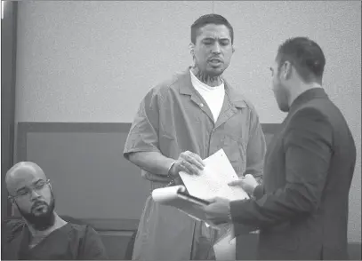  ?? JAmES TENSuAN/ LAS VEGAS REVIEW JOURNAL ?? Former mixed martial artist Jonathan Koppenhave­r, also known as War Machine, gives a document to his lawyer Brandon Sua as they appear before Judge Elissa Cadish on Wednesday. War Machine is being tried in connection with the beating of a former...