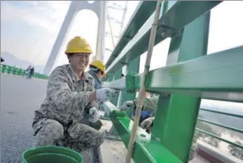  ?? XINHUA ?? GHATG workers painta bridge that connects Lanzhou city and Yongjing county in Gansu province as a part of maintenanc­e work.
