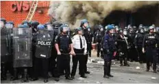  ?? AFP ?? Thin blue line Baltimore Police form a perimeter around a looted and burnt store on Monday.