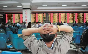  ?? — Reuters ?? An investor looks at an electronic board showing stock informatio­n at a brokerage house in Nanjing, China.