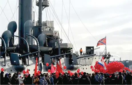  ?? — AFP photo ?? Communist party supporters hold red balloons in front of the Bolshevik’s revolution flagship Aurora cruiser as they take part in a rally marking the 104th anniversar­y of the Bolshevik Revolution also known as the October Revolution in Saint Petersburg.