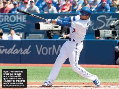  ??  ?? Ryan Goins étire les bras pour claquer une solide double qui a permis à deux coureurs de croiser le marbre en première manche. PHOTO2REUT­ERS