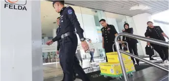  ?? AMIRUL SYAFIQ/ THESUN ?? MACC officers removing documents from the office of Felda Investment Corporatio­n yesterday.