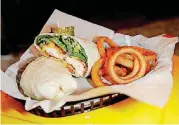  ?? [PHOTOS BY SARAH PHIPPS, THE OKLAHOMAN] ?? Hot chicken wrap and onion rings are pictured at Nashbird in Oklahoma City.