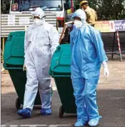  ?? PTI ?? Medical staff, wearing protective suits, hold medical waste as they exit the Special Isolation Ward set up to provide treatment to novel coronaviru­s patients at Kochi Medical college, in Kerala, Wednesday