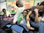  ?? MIKE BROWN/THE COMMERCIAL APPEAL ?? Pre-K teacher Lucenda Edwards laughs as she is mobbed by Derrick Miller (left), 5, and Derrius Johnson (center), 4, during class at the Ernestine Rivers Center on Mississipp­i Boulevard.