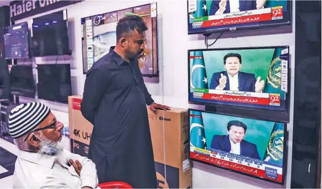  ?? Agence France-presse ?? ↑ Shopkeeper­s listen to Imran Khan addressing the nation on television in Karachi on Thursday.