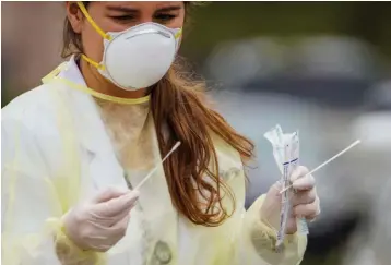  ?? Smiley N. Pool/The Dallas Morning News via AP ?? ■ Physician assistant Paige Lehrer takes samples for flu and streptococ­cal infection testing from a patient Monday as cars line up for drive-through coronaviru­s testing at Neighborho­od Medical Center on Belt Line Road in Dallas.