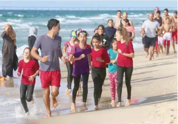  ?? — AFP ?? Young Palestinia­n members of a swimming club, run on the beach during a training session in Beit Lahia in the northern Gaza Strip.