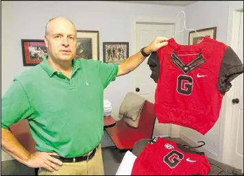  ?? MARK DAVIS / MRDAVIS@AJC.COM ?? Charles Seiler, who took over Uga duties from his father 10 years ago, has a selection of jerseys from previous UGA mascots. Included in the selection are attire for BatDawg and SuperDawg.