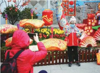  ??  ?? A parent takes a photo of her child at Guyi Garden which has finished the first phrase of the renovation project with Yiye Hall and the Pavilion of Birds Soaring and Fish Leaping reopening to the public. — Yu Chao