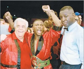  ?? Ron Frehm Associated Press ?? THE ‘SWEET’ TASTE OF VICTORY Pernell Whitaker celebrates with trainer Lou Duva, left, after referee Larry Hazard raised his hand to declare him the winner over James “Buddy” McGirt in 1993, earning him his third world championsh­ip.