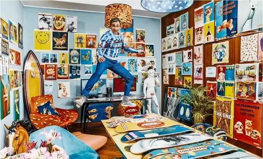  ??  ?? PIERPAOLO FERRARI, vêtu d’un sweatshirt ( ToiletPape­r pour MSGM) et de baskets (Santoni), au- dessus d’une collection de skates illustrés de ses visuels. Posters de ToiletPape­r, chaises, tapis et lampe (Seletti).