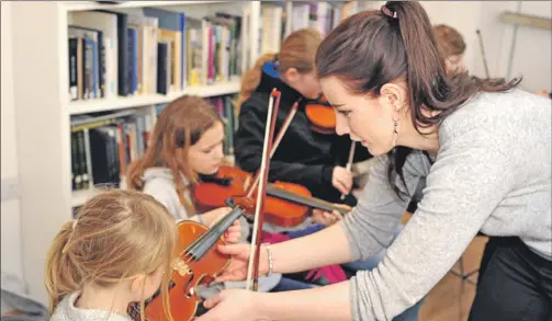  ??  ?? Tutor Niamh MacKaveney works with members of the junior fiddle class. Some of the young musicians were using newly-purchased fèis instrument­s.