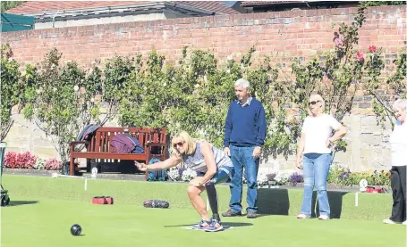  ??  ?? Bob Christie of Bowls Scotland coaches one of the amputee bowlers at Balgay Bowling Club.