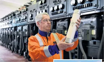  ?? PHOTOS: STEPHEN JAQUIERY ?? Heavy duty . . . Aurora asset reliabilit­y engineer David Paterson holds a 6.6kV, 160amp HRC fuse at the soontobede­commission­ed Neville St substation. Right: The exterior of the Neville St substation.