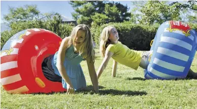  ?? BY LISA RAMEY ?? WCDS students Liza Dareing and Anika Pruntel take a tumble while playing in inflated carnival boppers.