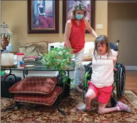  ?? ?? Kathy Dwyer helps her daughter Jen,
a 44-year-old woman with intellectu­al and developmen­tal disabiliti­es, get out of her wheelchair to dance on the floor and sing to Mariah Carey Christmas carols Sept. 17 at their home in Metairie.