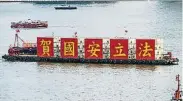  ??  ?? ← 一艘船架着“贺国安立法”黄字红底5个大刊版在­香港维多利亚港巡游。（法新社照片）