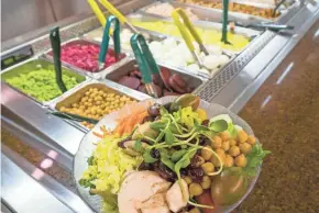 ??  ?? The salad bar at University Hospital includes updated foods and color-coded utensils to indicate healthier options.