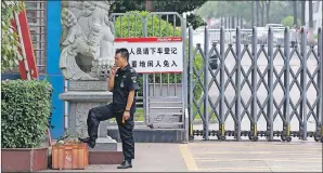  ?? AP PHOTO ?? A security guard smokes near a main entrance gate of the Ganzhou Huajian Internatio­nal Shoe City Co.’s factory, which has made shoes for the Ivanka Trump brand, in Ganzhou in southern China’s Jiangxi Province. The sign reads “visitors please exit the...