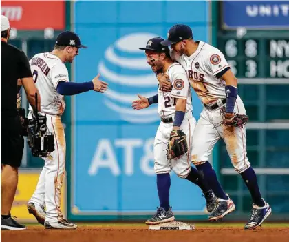  ?? Karen Warren / Houston Chronicle ?? Houston Astros third baseman Alex Bregman (2), second baseman Jose Altuve (27) and shortstop Carlos Correa (1) celebrate the Astros win over the Yankees on Friday night. The win forces Game 7 to decide the ALCS and who goes to the World Series.