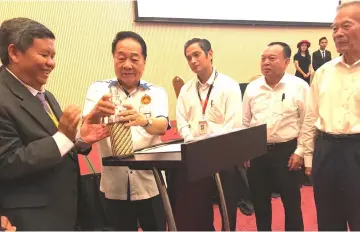  ??  ?? Wong (second left) inserts a letter into a bottle (time capsule) to declare open the celebratio­n while Siaw (left), Tiong (right) and others look on.