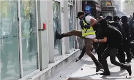  ??  ?? A protester kicks at the window of a bank in Paris. Photograph: Ian Langsdon/EPA