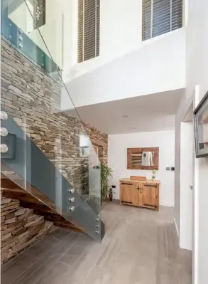  ??  ?? Right: The timber and steel staircase gives the property an industrial feel. Below: Full-height glazing helps to make the most of the views from the open-plan living area. Italian porcelain tiles extend the couple’s living space out onto the patio area