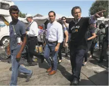  ?? Justin Sullivan / Getty Images ?? Candidate Julián Castro (center) tours an Oakland homeless camp with City Councilman Noel Gallo (right) last month.