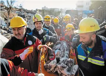  ?? BURAK KARA GETTY IMAGES ?? Rescue workers carry a survivor at the site of a collapsed building in Hatay, Turkey. The person was pulled from the rubble more than 60 hours after the 7.8-magnitude quake.