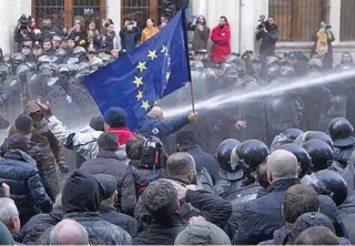  ??  ?? POLICE ACTION: Officers in helmets and riot gear gave the protesters 30 minutes to clear the area before using water cannon against the crowds escaping as they moved in.