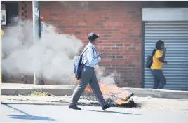  ?? Picture: Michel Bega ?? EVASIVE ACTION. Pupils hurry past burning tyres on New Canada Road in Noordgesig yesterday.