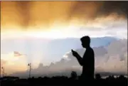  ?? ASSOCIATED PRESS FILE ?? A teenager checks his cellphone as storm clouds pass in Zionsville, Ind. A new poll by the Associated Press-NORC Center for Public Affairs Research says 12 percent of Americans use Facebook “almost constantly,” while 34 percent use it several times a...