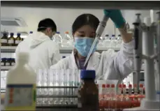  ?? AP PHOTO/NG HAN GUAN ?? In this Sept. 24 file photo, an employee of Sinovac works in a lab at a factory producing its SARSCoV-2 vaccine for COVID-19 named CoronaVac in Beijing. China is rapidly increasing the number of people receiving its experiment­al coronaviru­s vaccines, with a city offering one to the general public and a biotech company providing another free to students going abroad.