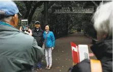 ?? Santiago Mejia / The Chronicle ?? Visitors take photos in front of the entrance to Muir Woods, which was closed during the partial shutdown in January.