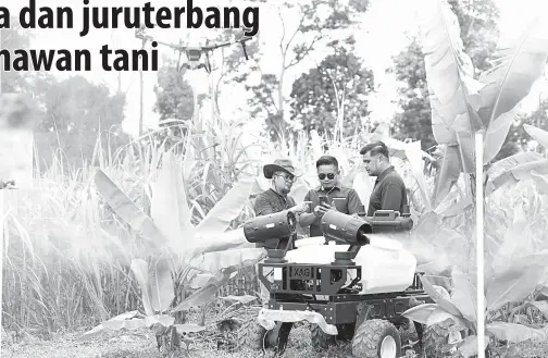  ?? — Gambar Bernama ?? CARA MODEN: Mohd Farid (tengah) melihat dron udara (UAV) dan darat (UGV) yang digunakan bagi meracun dan membaja di ladang integrasi moden di Labu Hilir dekat Nilai. Ladang itu mampu mengeluark­an hasil tanaman sehingga 200 tan setahun dengan potensi pulangan minimum RM600,000.