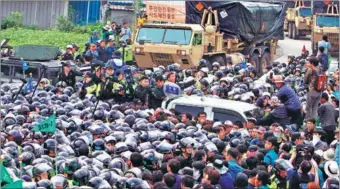  ?? YAO QILIN / XINHUA ?? ROK police officers try to keep residents and protesters from approachin­g US military trucks carrying components of the Terminal HighAltitu­de Area Defense missile system for deployment near Seongju on Thursday.