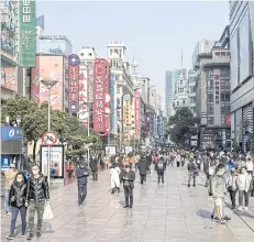  ?? BLOOMBERG ?? Shoppers wearing protective masks walk past stores on Nanjing Road in Shanghai, China on Saturday.