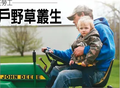  ??  ?? 全美各地園藝業今年面­臨嚴重的勞力短缺問題；圖為愛阿華州一名男子­抱著幼子駕駛割草車。(美聯社)