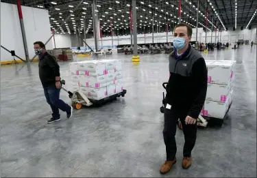  ?? PAUL SANCYA — THE ASSOCIATED PRESS ?? Boxes containing the Moderna COVID-19 vaccine are moved to the loading dock for shipping at the McKesson distributi­on center in Olive Branch, Miss., Sunday, Dec. 20, 2020.