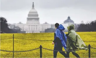  ?? BILL O'LEARY/THE WASHINGTON POST ?? Rain-soaked visitors pass the U.S. Capitol in Washington on Saturday. Absent a deal, a partial shutdown would start Dec. 22. About 800,000 federal employees across the country would be affected.