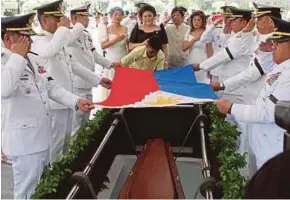  ?? AP pic ?? Military officials preparing to lower the coffin bearing the body of former president Ferdinand Marcos into a grave at the heroes’ cemetery in Manila yesterday. Looking on are Marcos’s wife, Imelda, and other relatives.