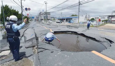  ?? — AFP ?? Police check a collapsed road following an earthquake in Takatsuki, north of Osaka prefecture, on Monday.