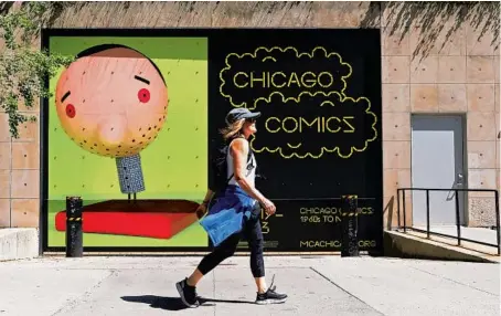  ?? ANTONIO PEREZ/CHICAGO TRIBUNE PHOTOS ?? A pedestrian passes a promotiona­l display for“Chicago Comics: 1960 to Now”outside the MCA.