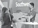  ?? TONY GUTIERREZ/AP ?? Southwest Airlines employee Oscar Gonzalez assists a passenger at the ticket counter at Love Field in Dallas.