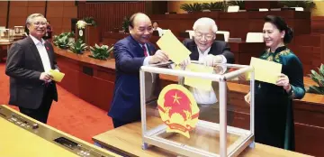  ?? — AFP photo ?? Trong (second right) casts his ballot to elect country’s president at the National Assembly hall in Hanoi.