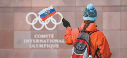  ?? FABRICE COFFRINI AGENCE FRANCE-PRESSE ?? Une passante agite un drapeau de la Russie en passant devant le siège social du CIO à Lausanne, en Suisse.